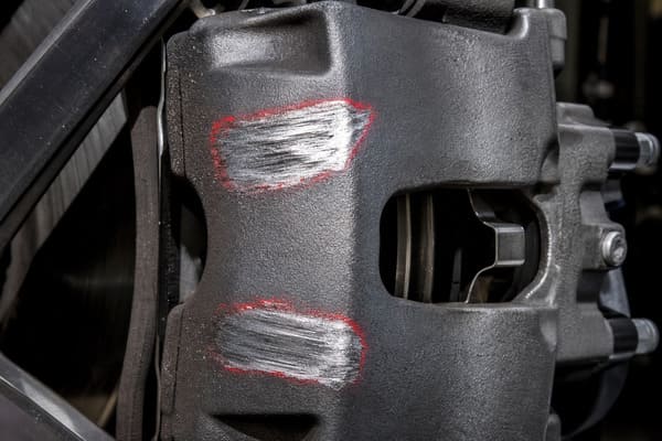Caliper Contact Damage from Insufficient Clearance Brake caliper with visible friction marks from wheel spoke contact